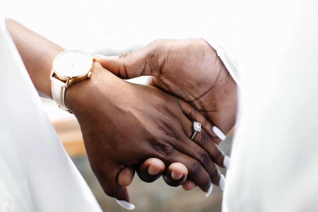 Couples hold hands with engagement ring